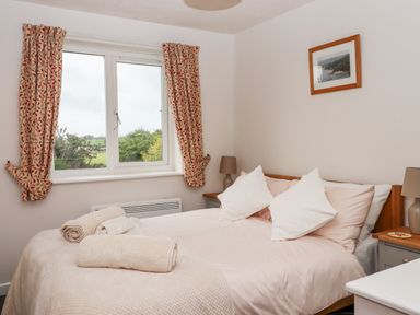 A bedroom with a double bed two bedside tables lamps and a window with curtains at Mabels View in East Allington Devon