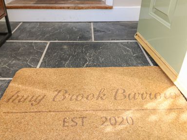 A floor with dark tiles and a welcome mat at Inny Brook Burrow in Davidstow near Camelford