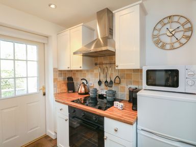 A kitchen area with a stove oven microwave kettle and utensils at Inny Brook Burrow Davidstow near Camelford