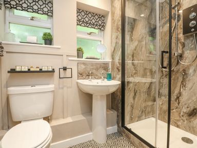 A bathroom with a toilet sink shower and patterned floor at Inny Brook Burrow in Davidstow near Camelford