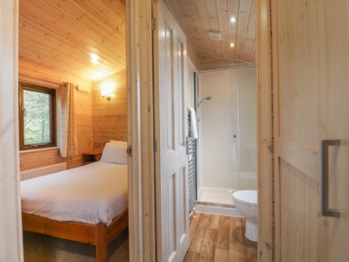 A bedroom with a bed and window next to a bathroom with a shower and toilet at Canadian Cabin No 39 in Keswick