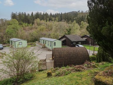 A group of small cabins and a wooden pod surrounded by trees and hills at Canadian Cabin No 39 in Keswick