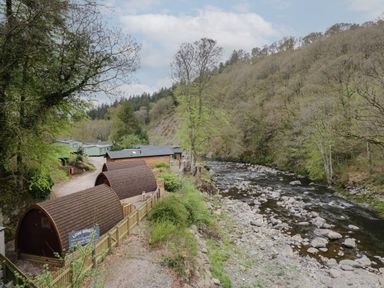 A riverside area with pod-shaped cabins and wooden houses surrounded by trees at Canadian Cabin No 39 in Keswick