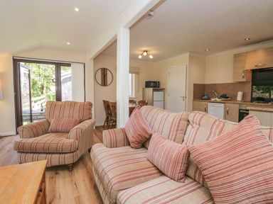 A living room with a sofa and dining area at Chestnut Timber Lodge in Keswick