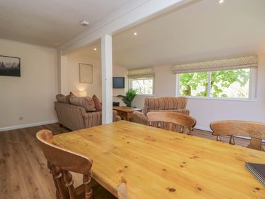 A living room with a dining table and sofa at Chestnut Timber Lodge in Keswick