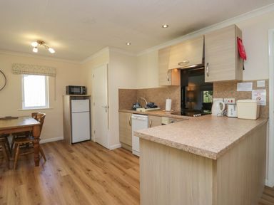A kitchen with wooden dining table and appliances at Chestnut Timber Lodge in Keswick