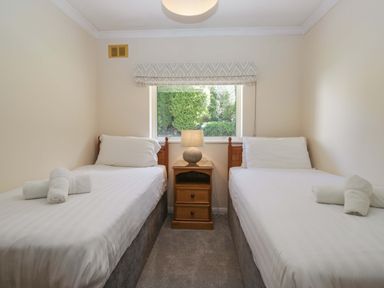 A bedroom with two single beds and a nightstand at Chestnut Timber Lodge in Keswick