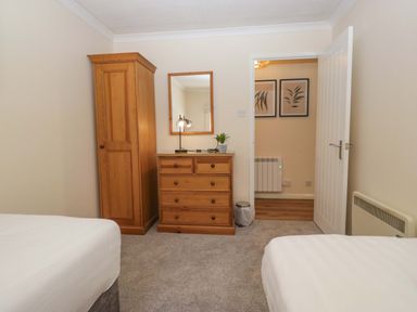 A bedroom with a bed, wardrobe, and chest of drawers at Chestnut Timber Lodge, Keswick