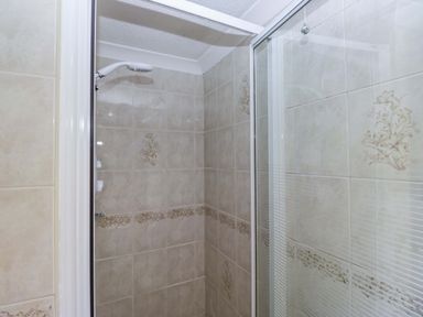 A shower area with tiles and glass door at Chestnut Timber Lodge in Keswick