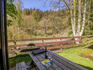 An outdoor table with a wine bottle and glasses at Chestnut Timber Lodge in Keswick