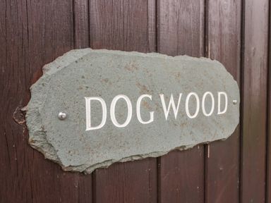A carved stone sign with the word dog wood mounted on a wooden surface at Dogwood Timber Lodge in Keswick