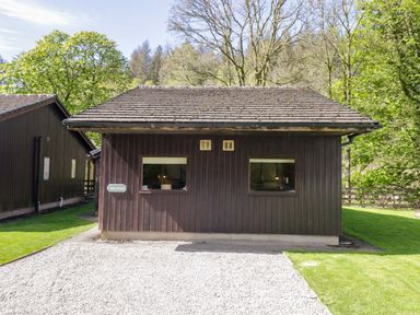 A wooden cabin with windows and a gravel path at Dogwood Timber Lodge in Keswick