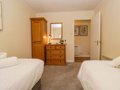 A bedroom with two beds and a wardrobe at Dogwood Timber Lodge in Keswick