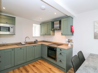 A kitchen with green cabinets and appliances at Riverside Cottage No 4 in Keswick