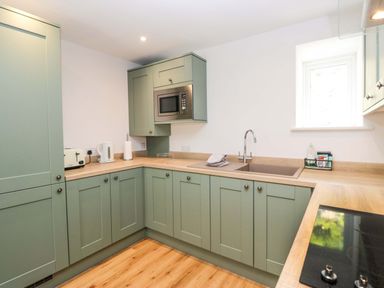 A kitchen with cabinets, sink, microwave, and kettle at Riverside Cottage No 4 in Keswick
