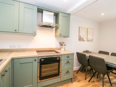 A kitchen with cabinets and a dining table at Riverside Cottage No 4 in Keswick
