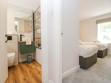 A bathroom with a sink and toilet next to a bedroom with two beds at Riverside Cottage No 4 in Keswick