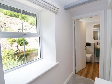A hallway with a window and a door to the bathroom at Riverside Cottage No 4 in Keswick