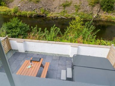 An outdoor area with a patio table and hot tub at Riverside Cottage No 4 in Keswick