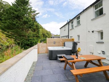 An outdoor area with a hot tub and wooden table at Riverside Cottage No 4 in Keswick