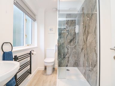 A bathroom with a shower enclosure toilet sink and towel rack at Chellowdene Cottage in Falmouth