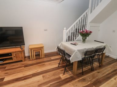 A dining room with a table and television at Chellowdene Cottage in Falmouth