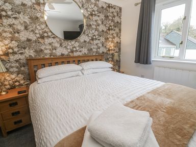 A bedroom with a bed and nightstand at Chellowdene Cottage in Falmouth