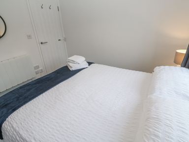 A bedroom with a bed and towels at Chellowdene Cottage in Falmouth