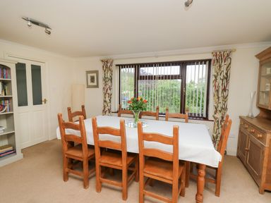 A dining room with a wooden table and chairs with a white tablecloth and flowers on the table at The Clove Poyston Cross near Haverfordwest
