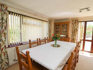 A dining room with a long table covered with a white tablecloth and wooden chairs at The Clove in Poyston Cross near Haverfordwest
