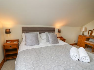 A bedroom with a double bed pillows bedside tables with lamps and a wooden dressing table at The Clove Poyston Cross near Haverfordwest