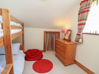 A bedroom with bunk beds a wooden dresser a red bean bag and a red circular rug at The Clove in Poyston Cross near Haverfordwest