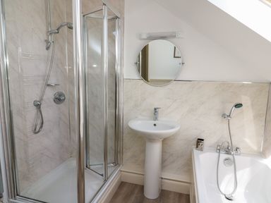 A bathroom with a shower enclosure a pedestal sink a round mirror and a bathtub at The Clove in Poyston Cross near Haverfordwest