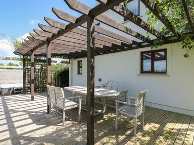 An outdoor wooden deck with a table and chairs under a wooden pergola at The Clove in Poyston Cross near Haverfordwest