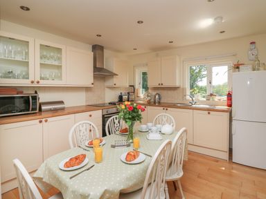 A kitchen with white cabinets wooden countertops and a dining table with croissants and orange juice at Lavender Lodge in Haverfordwest