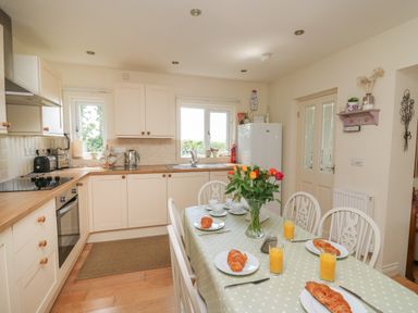 A kitchen with dining table set with croissants and orange juice at Lavender Lodge in Haverfordwest