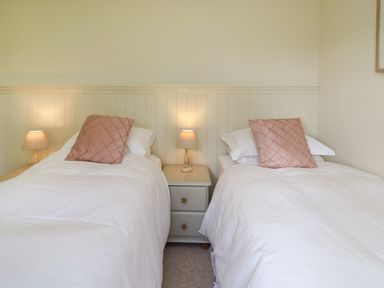 A bedroom with two single beds separated by a nightstand with a lamp at Lavender Lodge in Haverfordwest