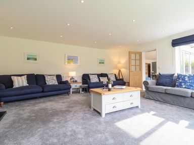 A living room with blue and gray sofas a wooden coffee table and framed pictures on the wall at Little Chapter in Walberswick