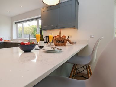 A kitchen countertop with a bowl of strawberries glasses of orange juice bottle of prosecco and a basket of croissants at Little Chapter in Walberswick
