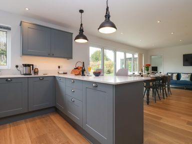 A kitchen and dining area with grey cabinets wooden floor and a dining table with chairs at Little Chapter in Walberswick