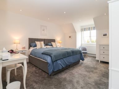 A bedroom with a double bed bedside tables lamps a chair and a window at Little Chapter in Walberswick