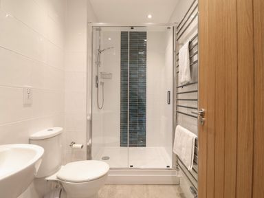 A bathroom with a toilet sink shower with glass doors and towel rack at Little Chapter in Walberswick