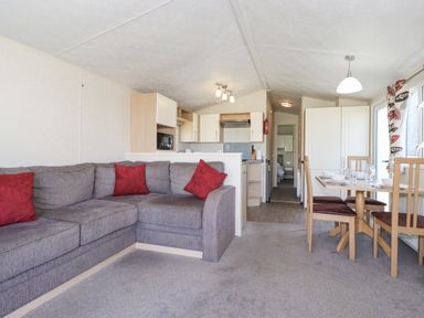 A living area with a gray sectional sofa with red pillows an open kitchen and a dining table with chairs at Swinside in Lorton