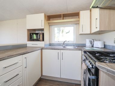 A kitchen with a sink under a window a microwave stove kettle toaster and cabinets at Swinside in Lorton