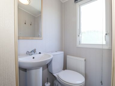 A bathroom with a pedestal sink a toilet a window and a radiator at Swinside in Lorton