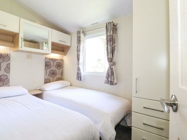 A bedroom with two single beds a window with curtains and a wardrobe at Swinside in Lorton