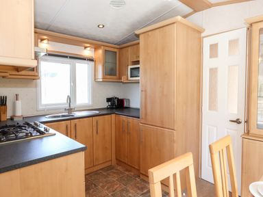 A kitchen with wooden cabinets a gas stove a sink and a window at Whiteside in Lorton
