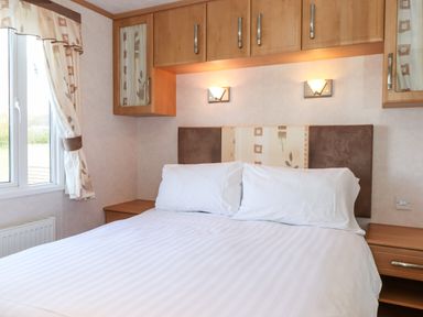 A bedroom with a bed white pillows white striped bedding wooden cabinets on the wall curtains on a window at Whiteside in Lorton