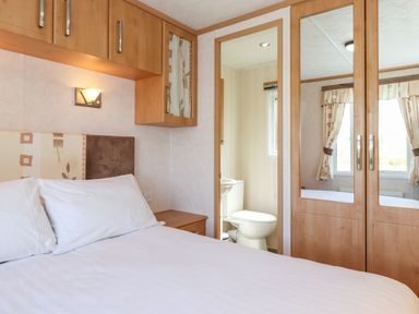 A bedroom with a bed white pillows wooden cabinets and a view into a small bathroom at Whiteside in Lorton