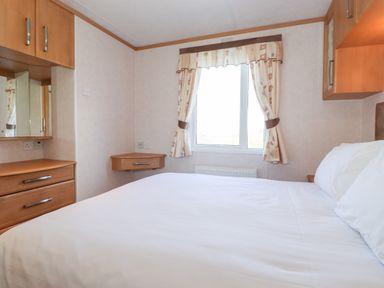 A bedroom with a bed white bedding a window with curtains wooden drawers and cabinets at Whiteside in Lorton